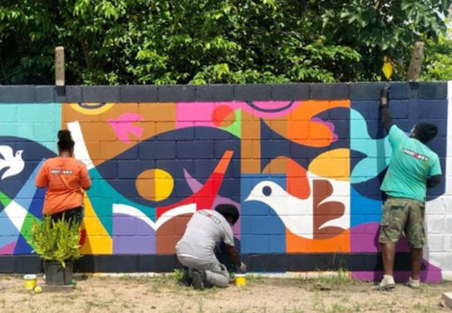 volunteers painting a mural on a wall