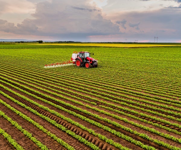 Red tractor with equipment feeding a freshly ploughed field