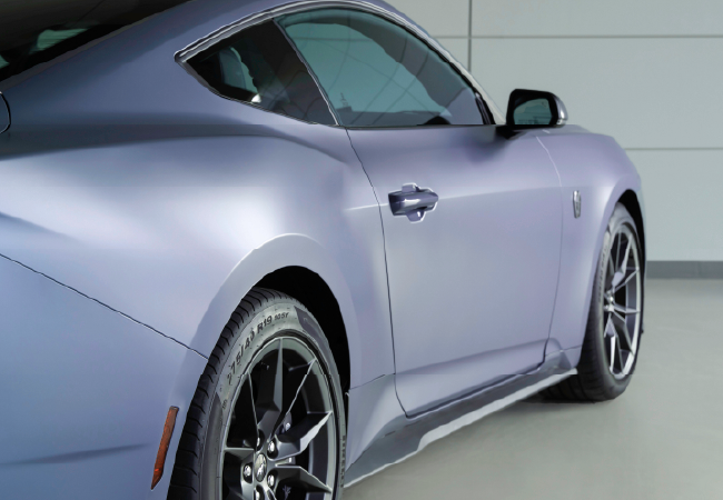 Side profile of a silver sports coupe indoors, highlighting smooth body contours, wheels, and door design.