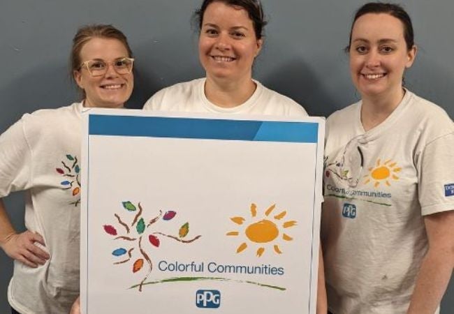 three women holding a colorful communities sign in Pittsburgh, Pennsylvania 