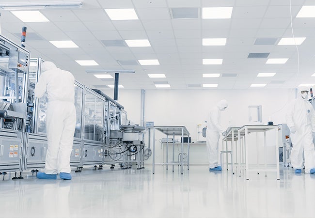 A group of people in white hazmat suits in a factory