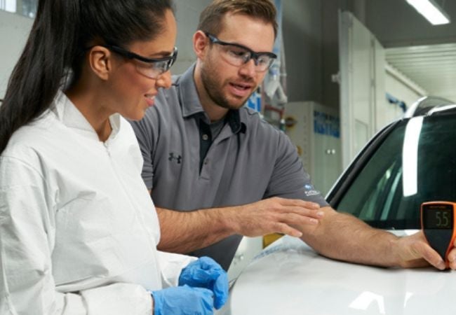 two workers looking at car