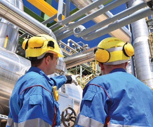 Two workers wearing PPE examining pipework