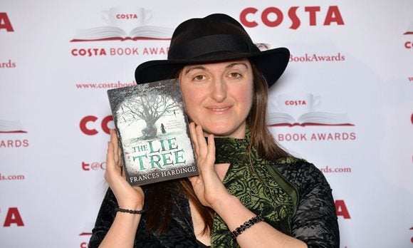 Portrait of Frances Hardinge holding a copy of her Book the Lie Tree