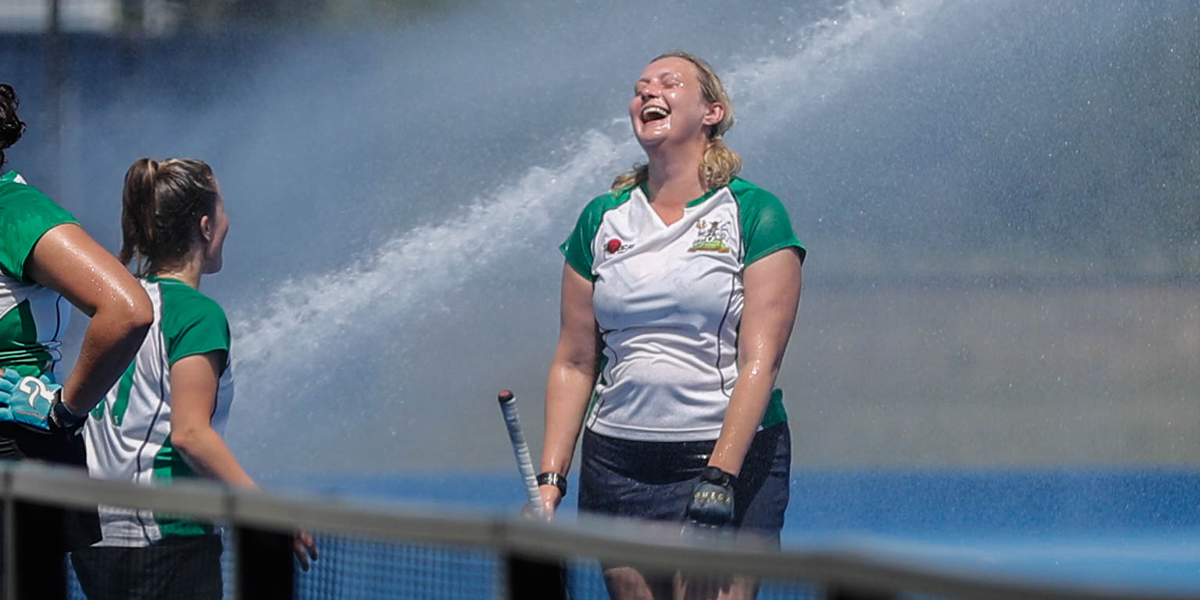 female player smiling in water from cannon in the sunshine