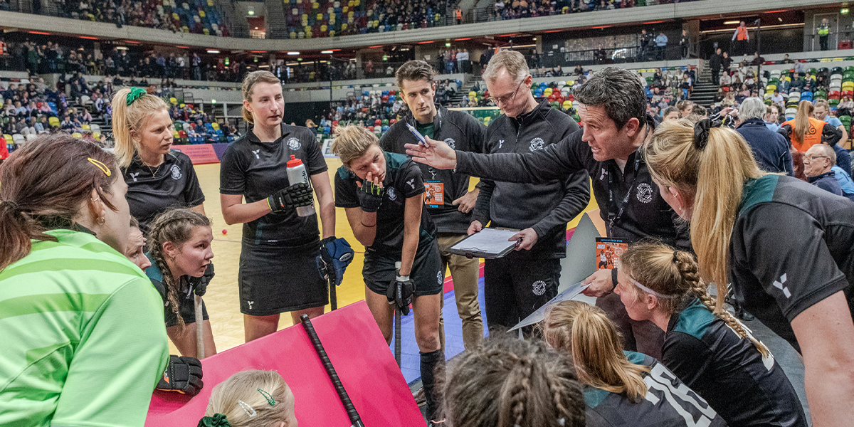Coach talking to female players at super 6s indoor hockey