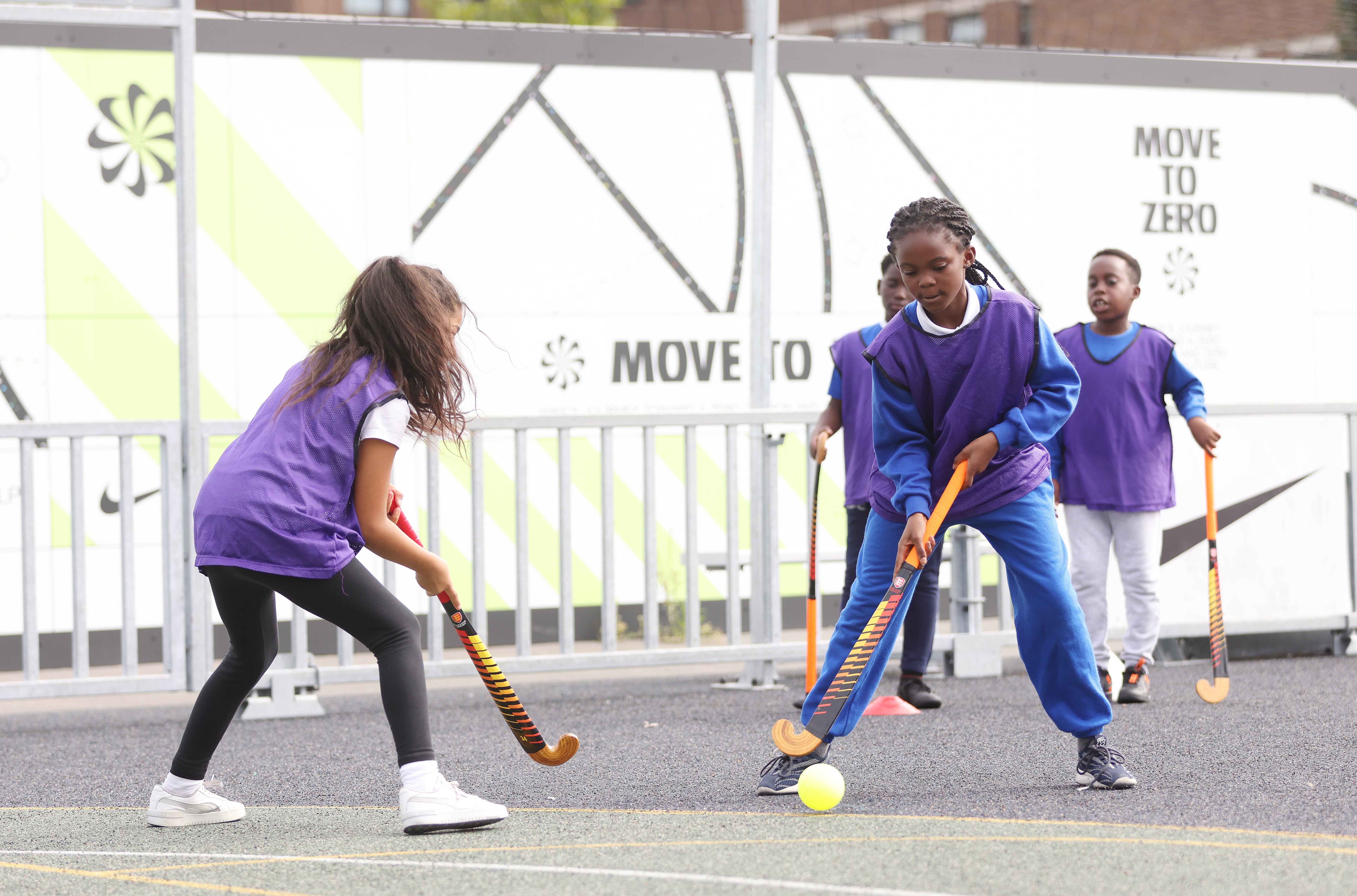 Girls playing hockey on a playground