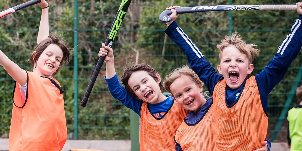 young players smiling with hockey sticks and bibs on 