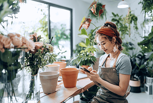 A business owners sits in her florist and compares business energy suppliers on her phone