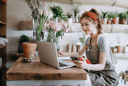 A business owner sits at a laptop in her florist and compares rates