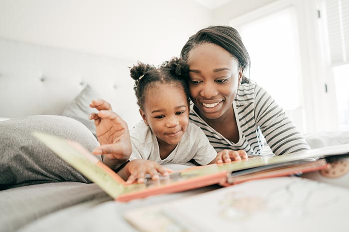 Mother and daughter on a bed looking at a book together