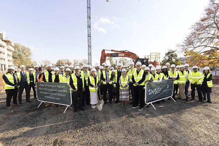 A group of people with a shovel standing next to a digger