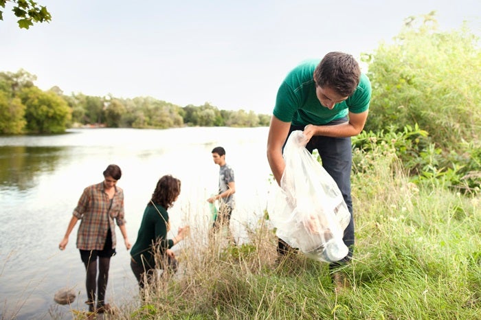 A group of young people litter picking by a river