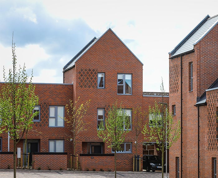 Red brick apartment block with young trees planted outside