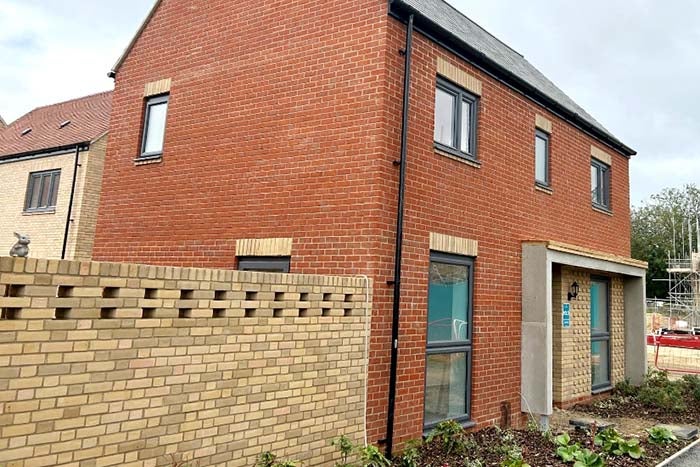 A red brick home being built. The home is nearly finished.