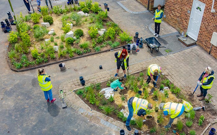 A group of people wearing hi-vis jackets, working in a community garden