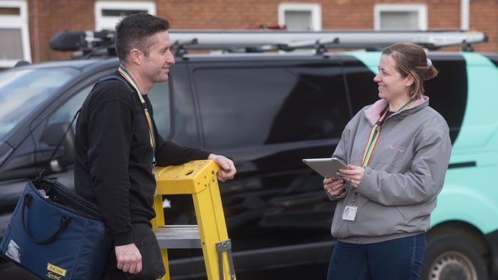 SNG trades employee talking to a colleague in front of a work van