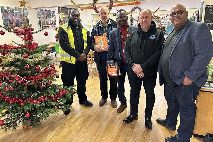 Photo of staff with defibrillator. Left to right: Abiola Agbabiaka, Resident Liaison Officer at Higgins, Tim Goodwin, Regeneration Manager at SNG, Julian Adje, Stockwell Park Community Trust Administrator, Ryan Kelly, Contracts Manager at Kingsbury Construction and Hitesh Bhudia, Managing Director at Kingsbury Construction.