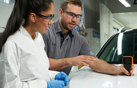 Workers examining coatings on car bodywork