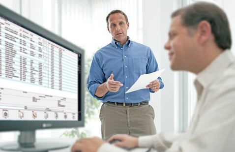 Two employees discussing stats on computer screen