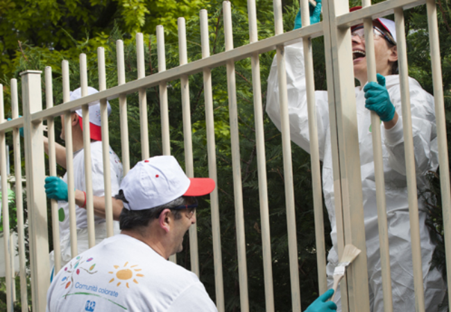 Volunteers painting gate tan in Alessandria, Italy 