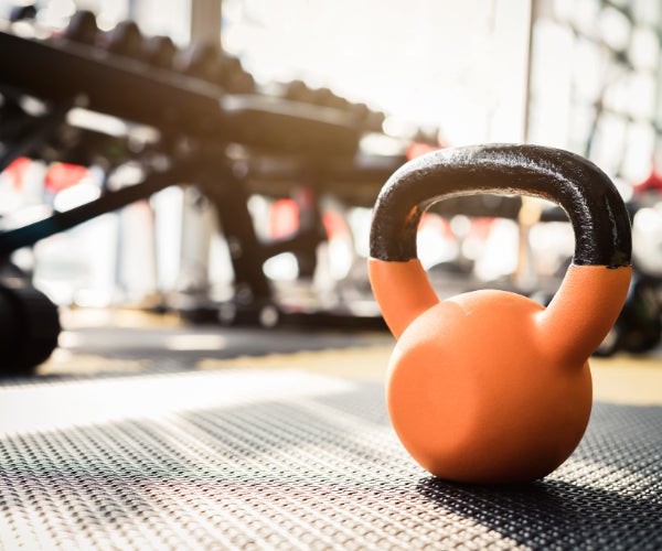 Orange kettle bell with a black handle in a gym