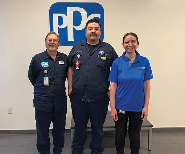 PPG employees in uniform next to PPG sign