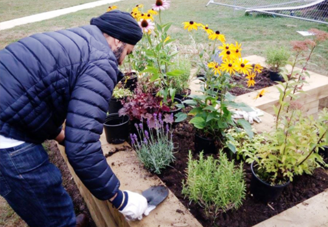 man tending to flower beds in Birstall, UK 