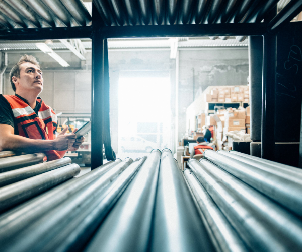 Worker stood at the side of a shelf holding metal pipes