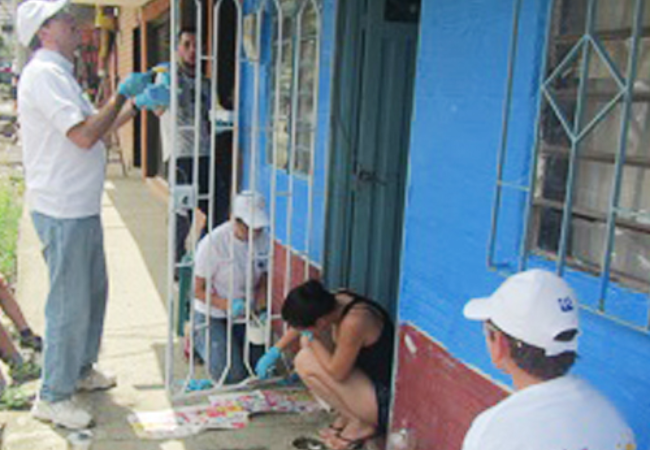 Group of volunteers painting house exterior in Itagui, Antioquia