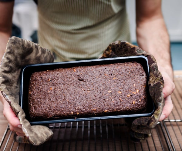 Baking tray with cake being held with oven gloves