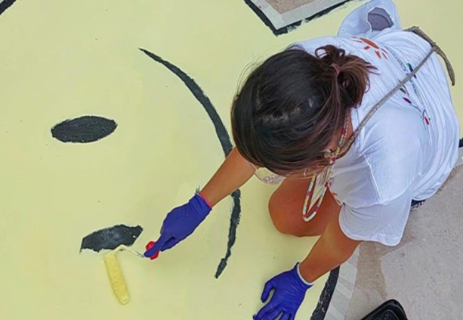 girl painting smiley face mural 