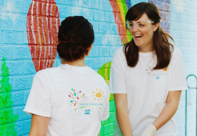 two girls laughing in front of mural 