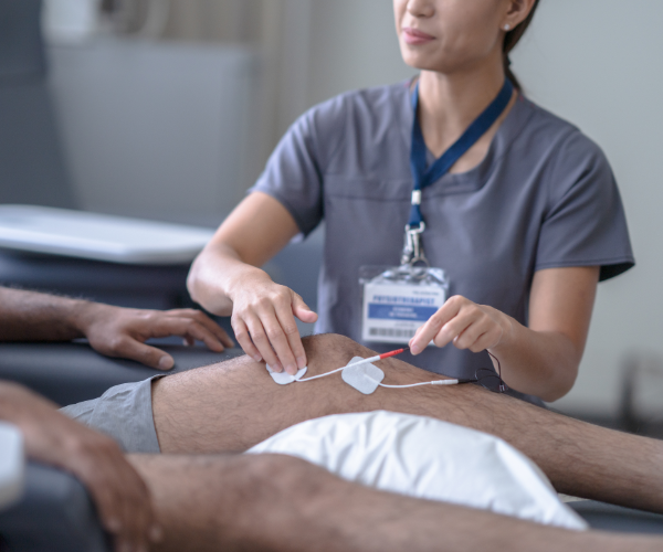 Woman delivering physiotherapy to a male knee using pulse circuitry