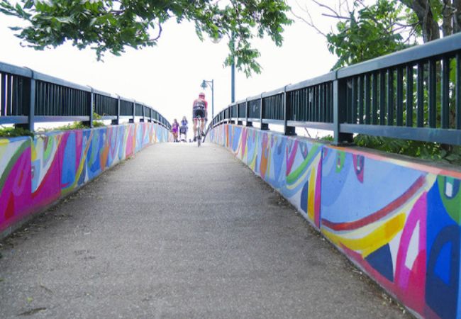 painted pedestrian foot bridge with bikers crossing 