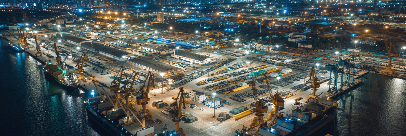 Skyline view of a night lit shipping harbor with containers, cranes and storage buildings