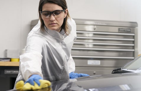 Female worker polishing car bodywork