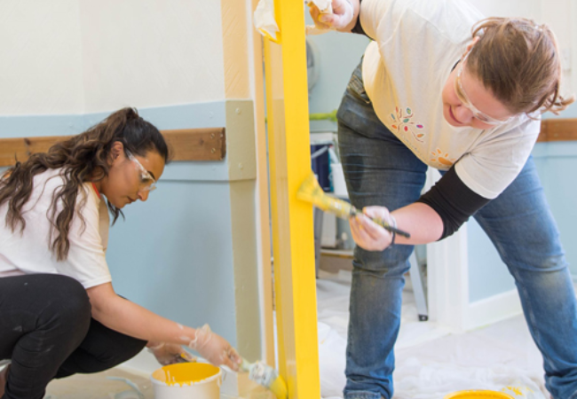 volunteers painting wall yellow