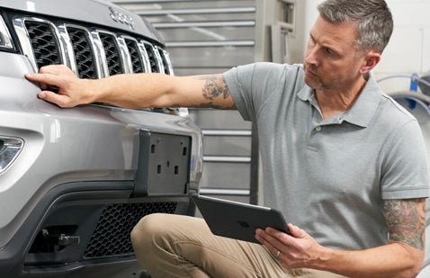 Man holding tablet and inspecting vehicle bodywork