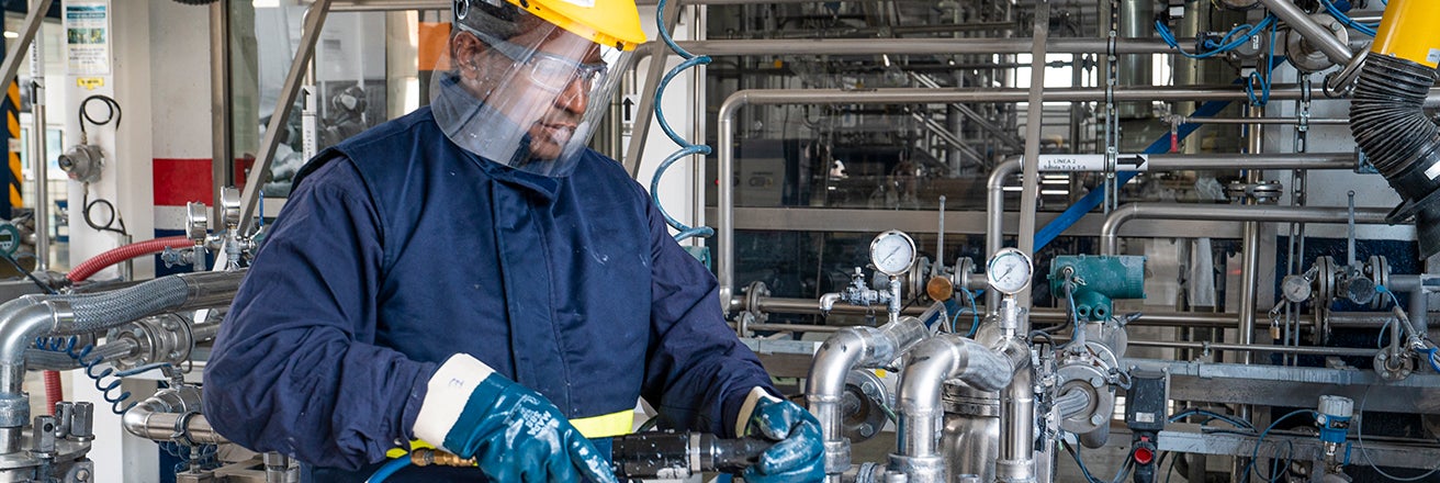 PPG employee in full PPE surrounded by equipment within facility