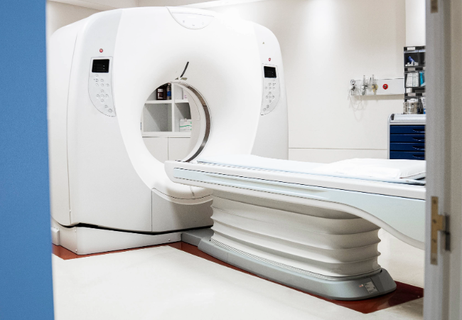 View through an open door of a modern MRI scanner in a hospital imaging room.