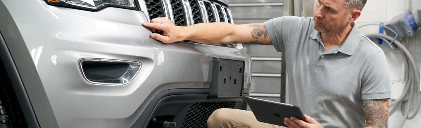 Man holding tablet and inspecting vehicle bodywork