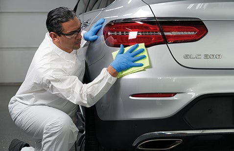 Technician wearing PPE polishing car panel