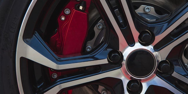 Close-up view of a car's alloy wheel featuring a multi-spoke design and a red brake caliper