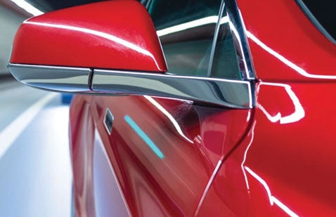 Close-up of red car wing mirror and side panel