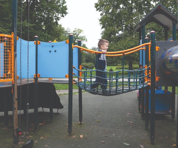 Young boy on a brightly colored playground walking over netting