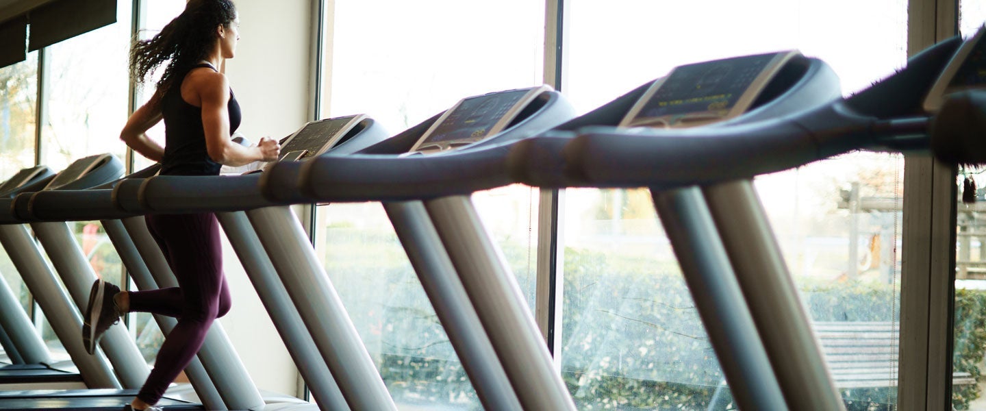 Athletic woman running on a treadmill in a gym filled with natural light