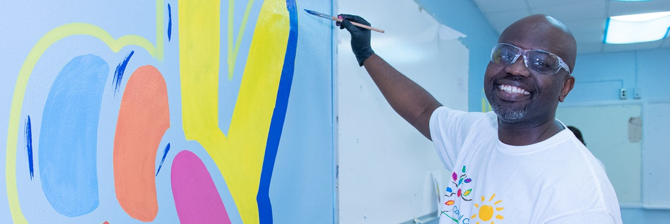 Person painting a colorful mural on a wall in a school classroom