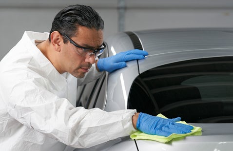 Man wearing PPE polishing car bodywork