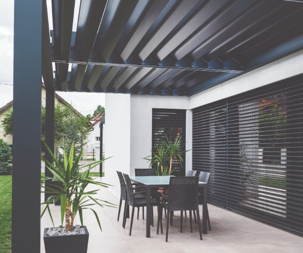 Black patio furniture outside a white and black building with green potted plants